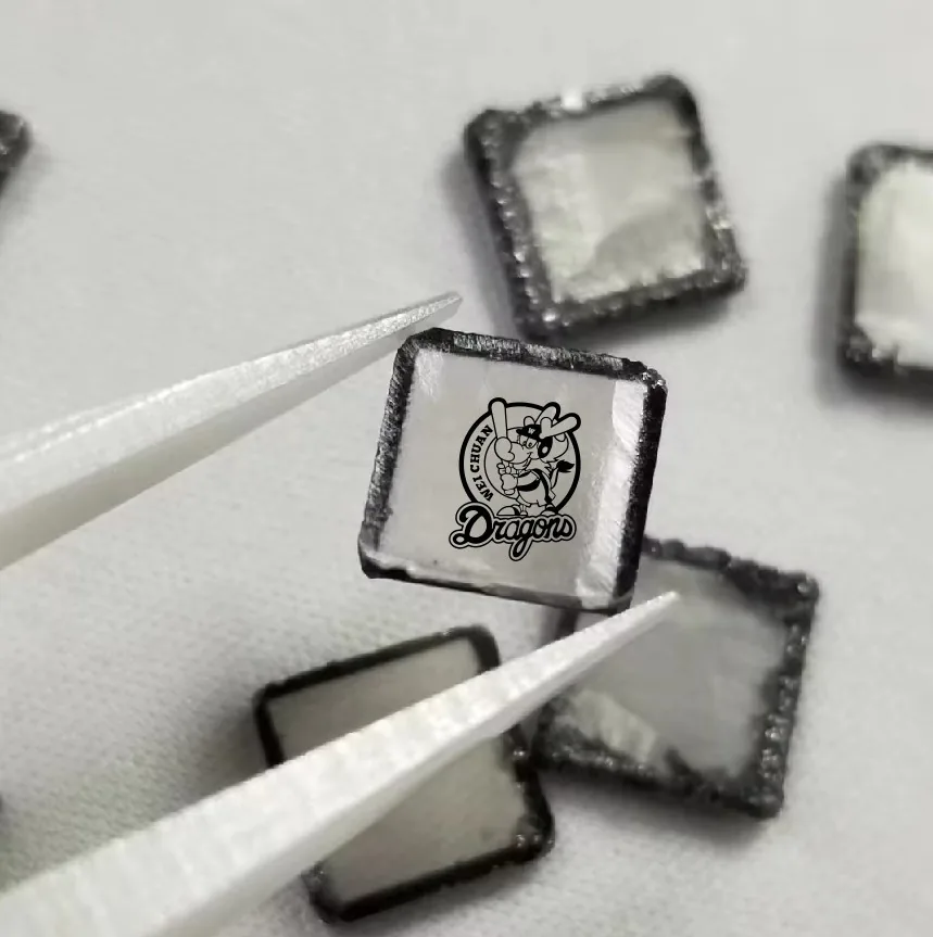 A brand logo engraved on a diamond held in tweezers