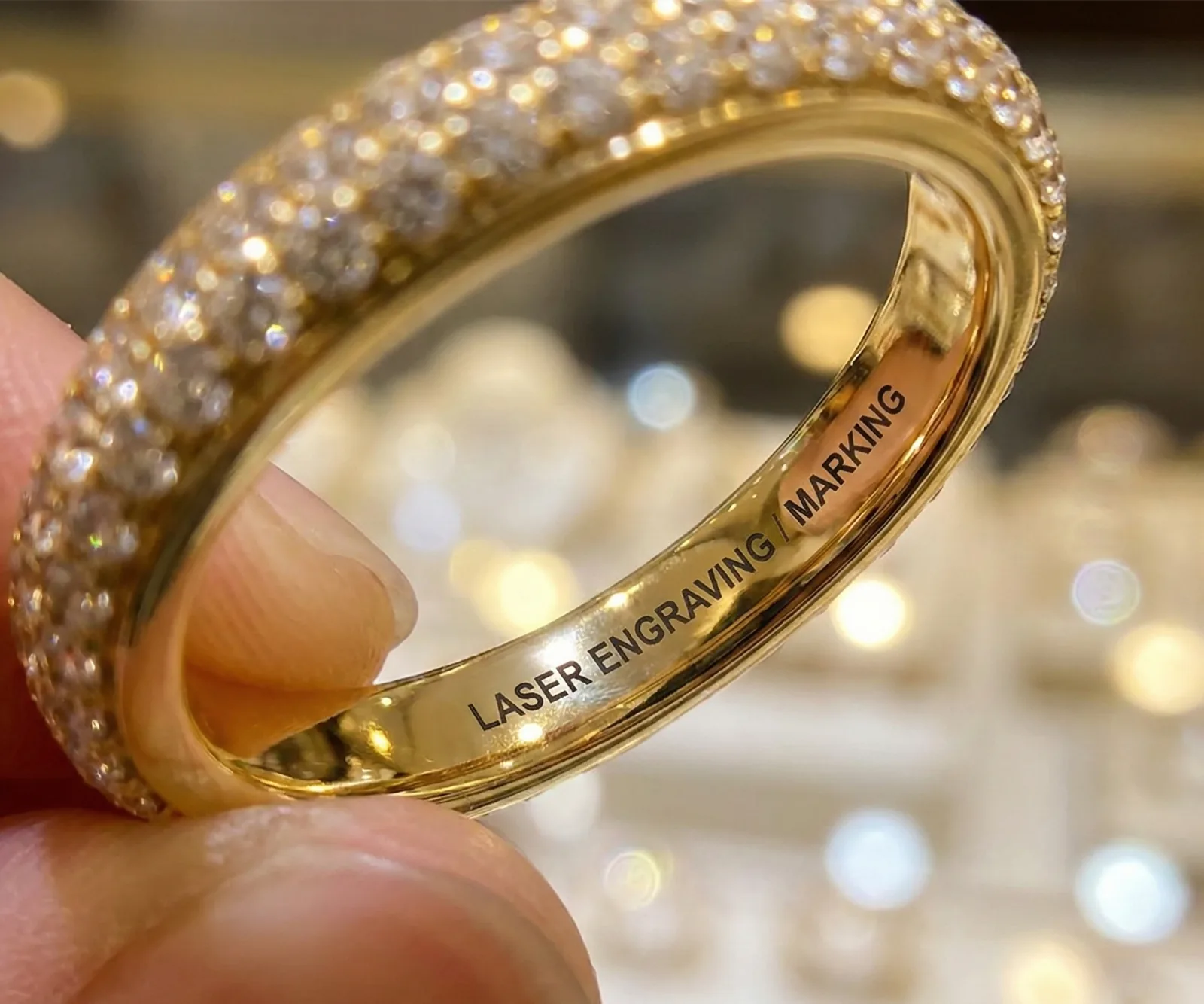 Ring held between fingers showing laser engraving inside
